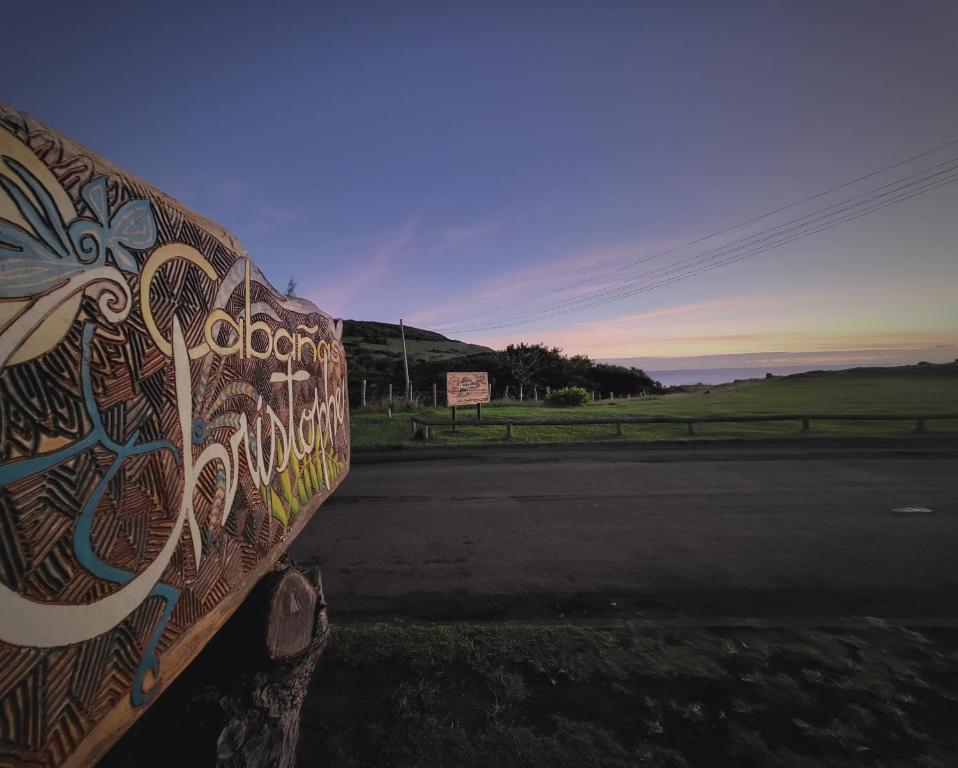 uma parede com graffiti no lado de uma estrada em Cabañas Christophe em Hanga Roa