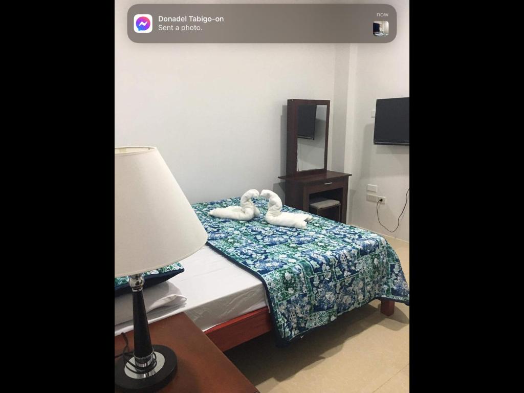 a hotel room with a bed with a lamp and a mirror at Donadel Hometel in Iloilo City