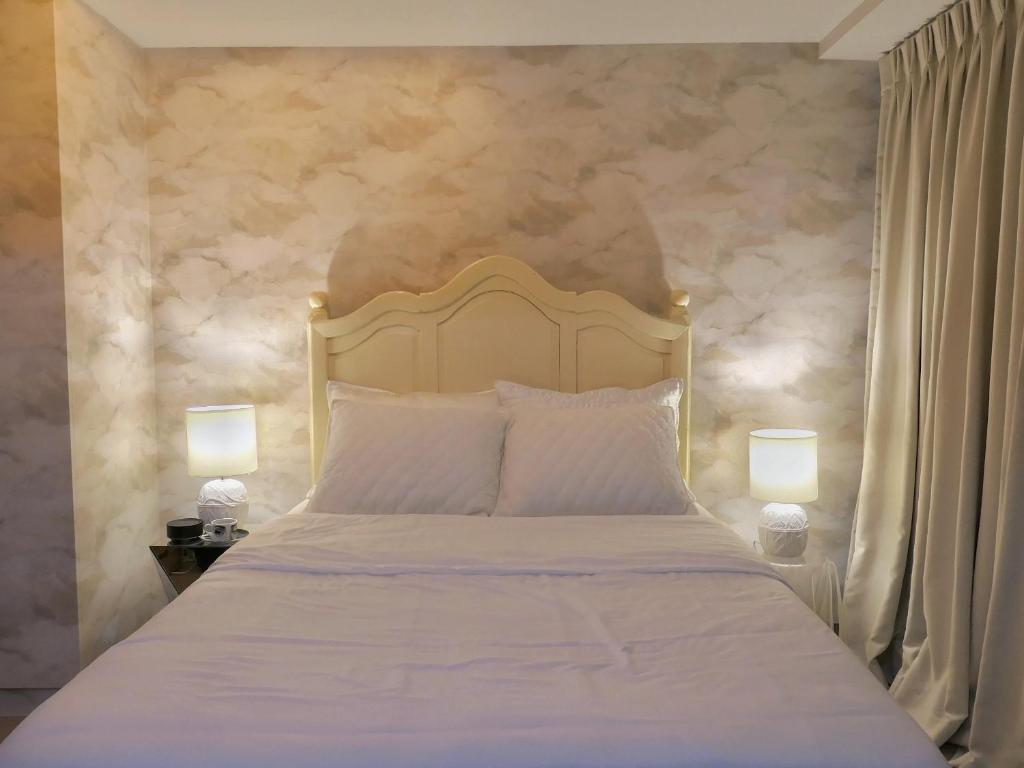ein Schlafzimmer mit einem weißen Bett mit zwei Lampen in der Unterkunft Uptown BGC Taguig - One Bedroom in Manila