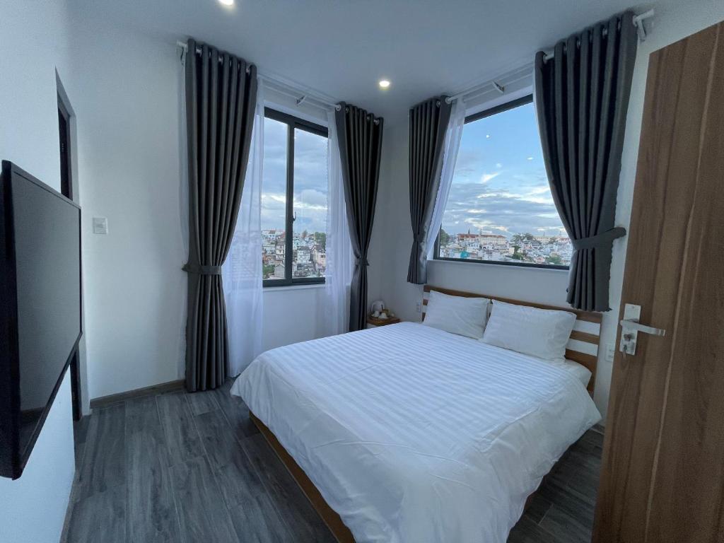 sypialnia z białym łóżkiem i 2 oknami w obiekcie Aloha Homestay "4 bedrooms - 1 kitchen - 1 terrace" w mieście Da Lat