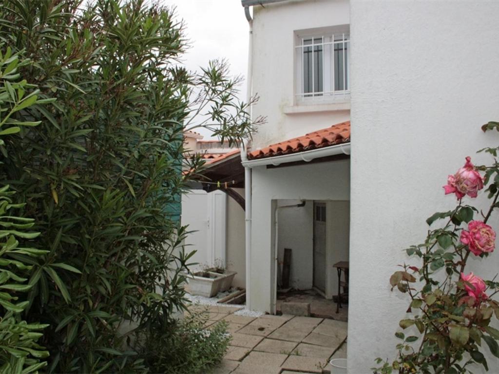 une entrée à une maison blanche avec un jardin dans l'établissement Maison raffinée au cœur de La Tranche, proche plage, parking et terrasse - FR-1-22-188, à La Tranche-sur-Mer