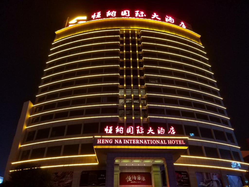 un gran edificio con letreros de neón por la noche en Hengna International Hotel, en Yiwu