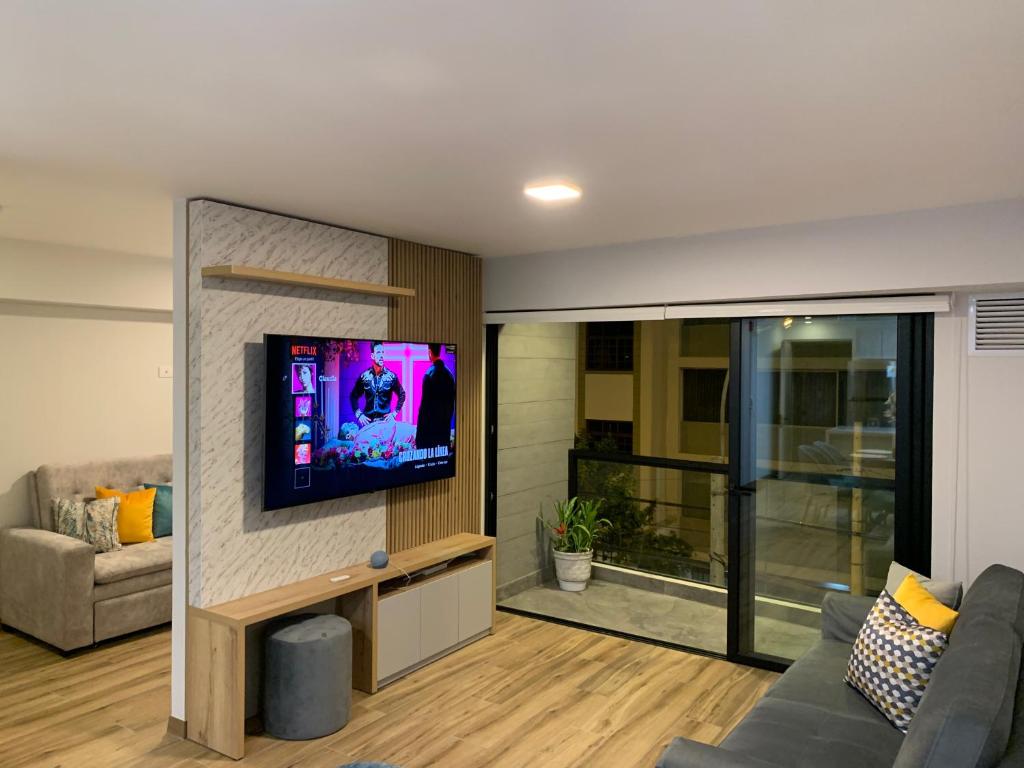 a living room with a couch and a tv on a wall at Apartamento en Miraflores con AC in Lima