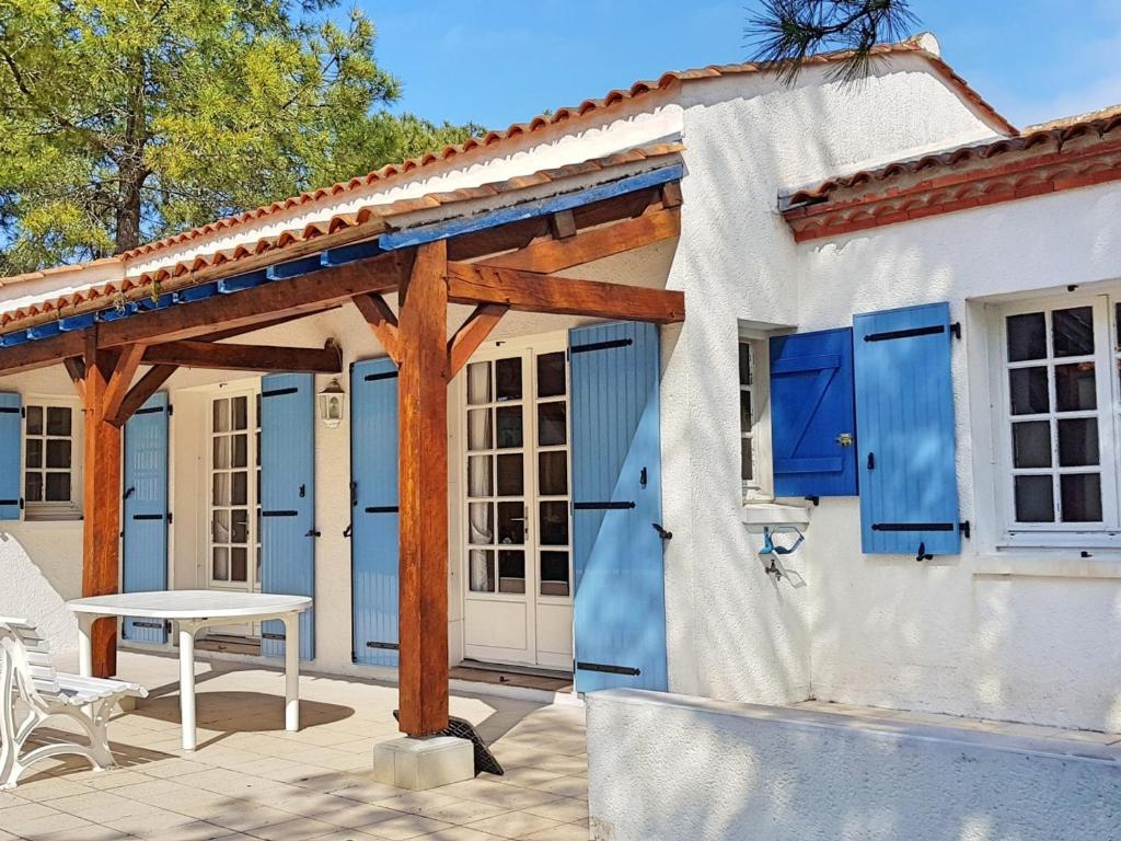 une maison avec des volets bleus et une table sur une terrasse dans l'établissement Maison de vacances au calme à 50m de la plage, La Tranche-sur-Mer - FR-1-22-299, à La Tranche-sur-Mer