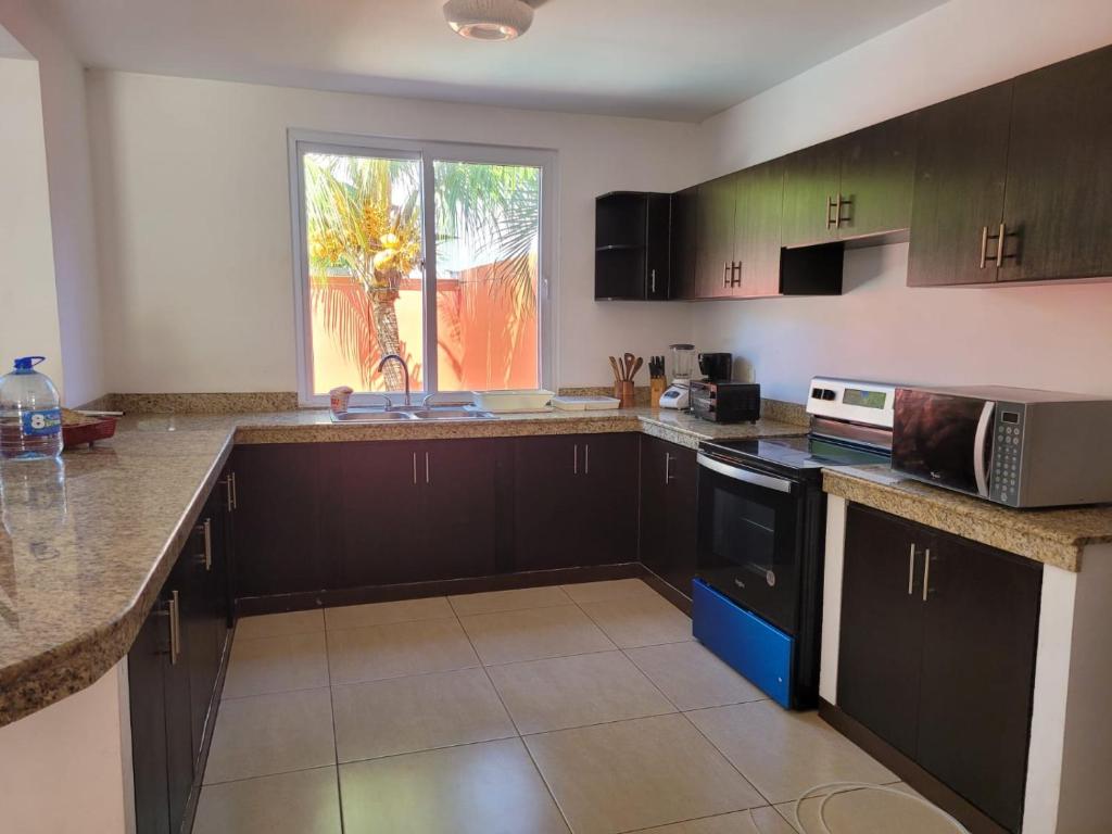 a kitchen with black cabinets and a sink and a window at Casa en condominio monterrico in Iztapa
