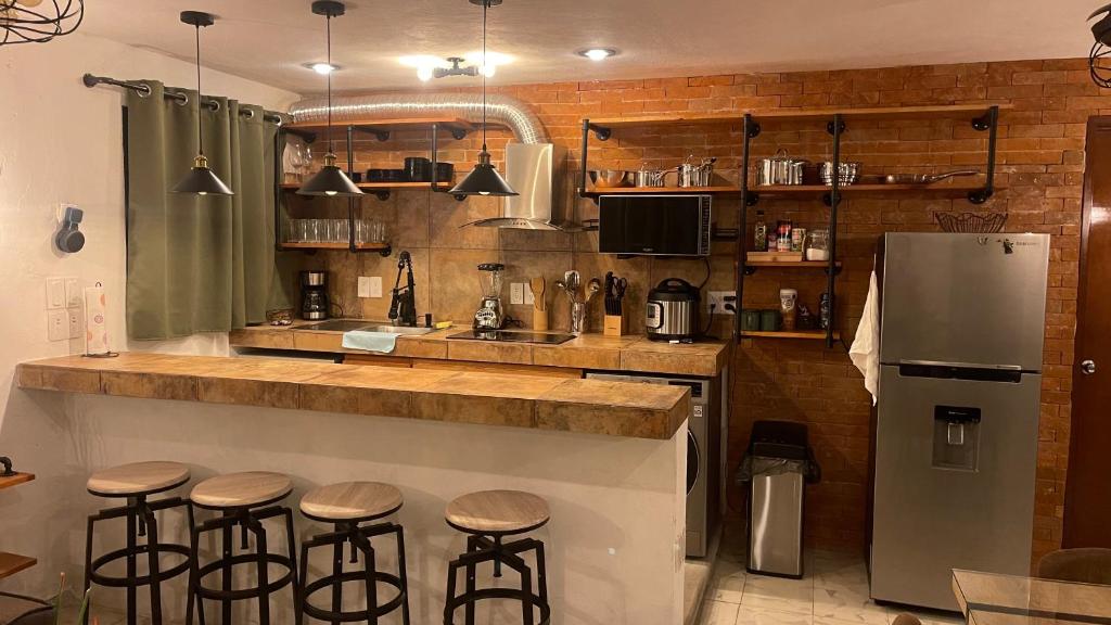 a kitchen with a bar with stools and a refrigerator at INDUSTRIAL.SMART HOME in Mérida