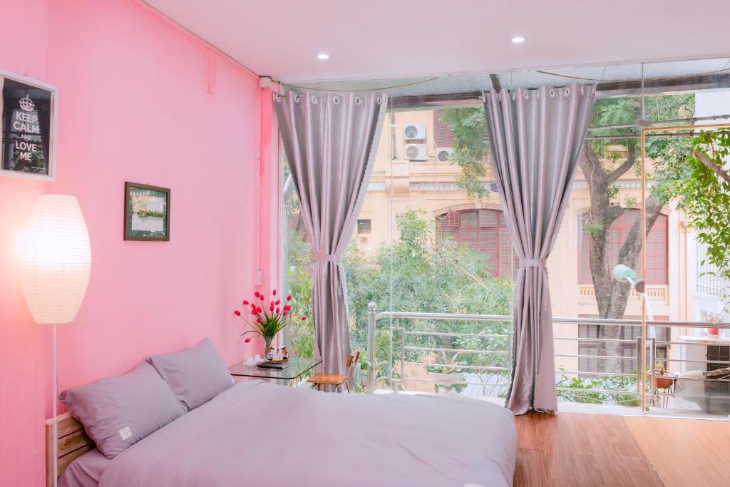 Habitación de color rosa con cama y ventana grande. en Kim's Homestay Center of Ha Noi en Hanói