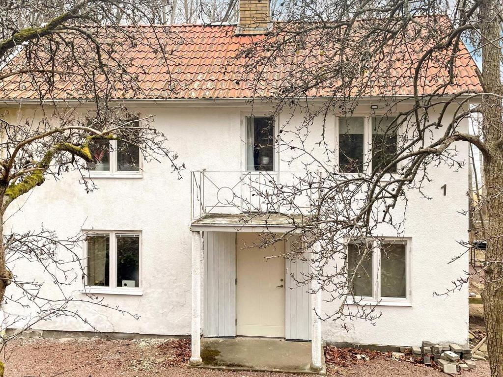 una casa blanca con una puerta blanca y un árbol en 4 person holiday home in GR NNA, en Gränna