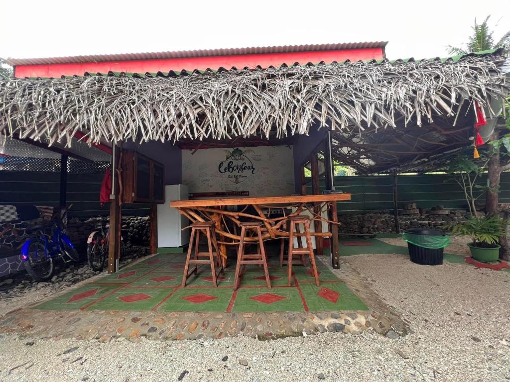 a restaurant with a table and stools under a straw roof at Moorea Vaiare Lodge in Moorea