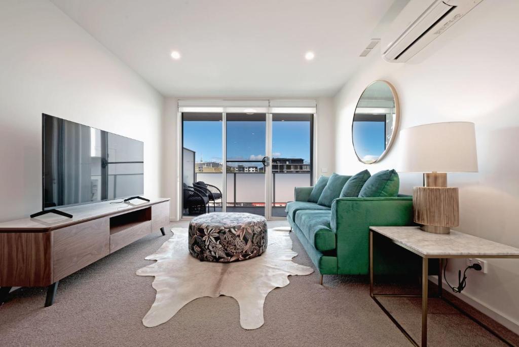 ein Wohnzimmer mit einem grünen Sofa und einem TV in der Unterkunft The Menzies Suite in Canberra