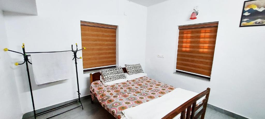 a small room with a bed and two windows at Forestay -3 BHK Villa Kochi in Pallipuram