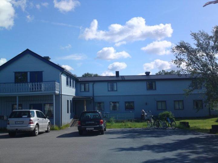 un gran edificio blanco con coches aparcados en un aparcamiento en Tana Vertshus en Bånjakas