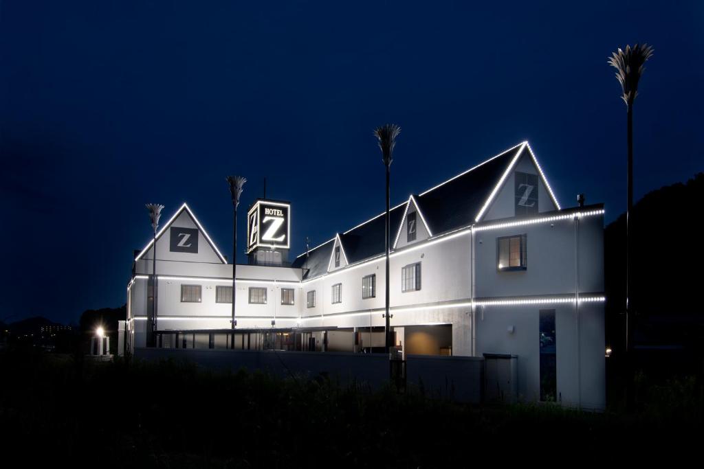 un edificio blanco con un cartel en él por la noche en HOTEL ZERO en Tatsuno