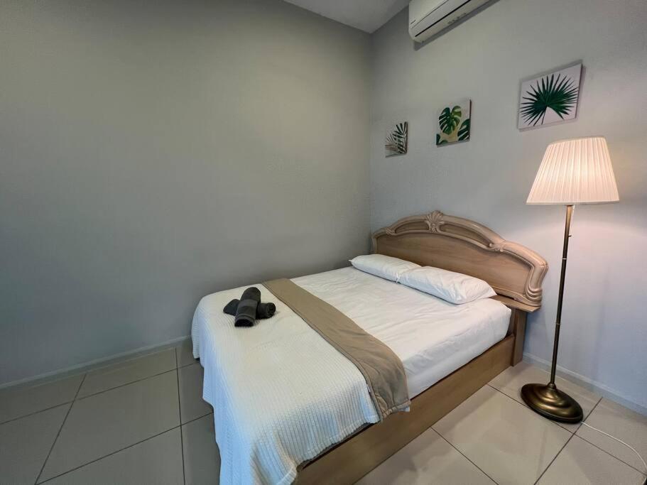 ein Schlafzimmer mit einem Bett mit einer Lampe und einem Hut darauf in der Unterkunft Entire Unit Pacific 63/JayaonePJ/Wifi/Pool/Balcony in Petaling Jaya