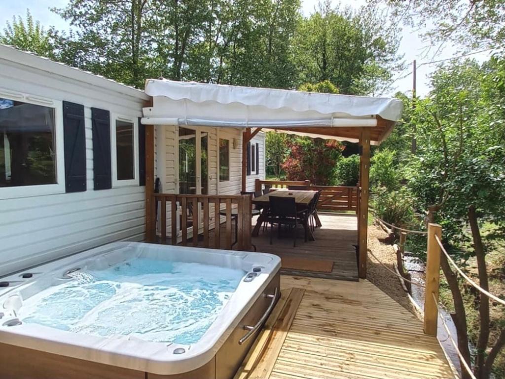 a hot tub on a deck with an umbrella at Le Mill in Meilhan