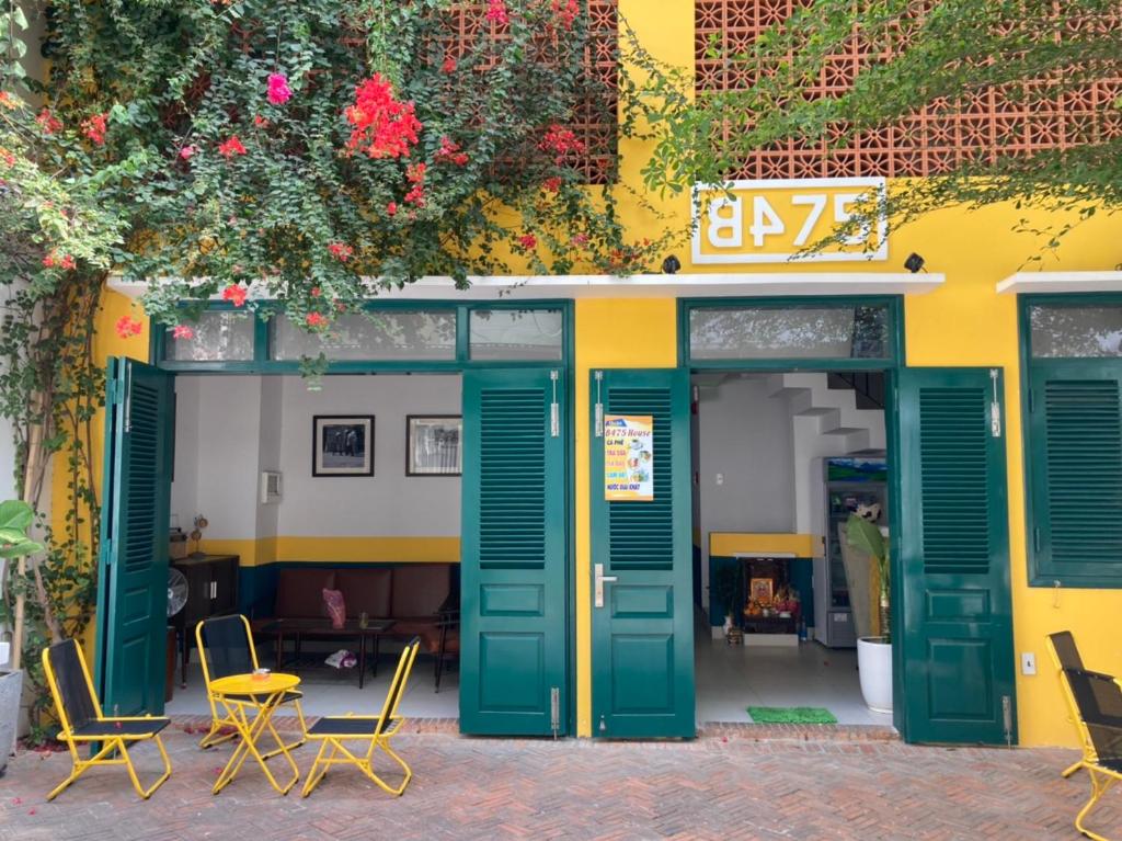a building with green doors and chairs and flowers at B475house in Nha Trang