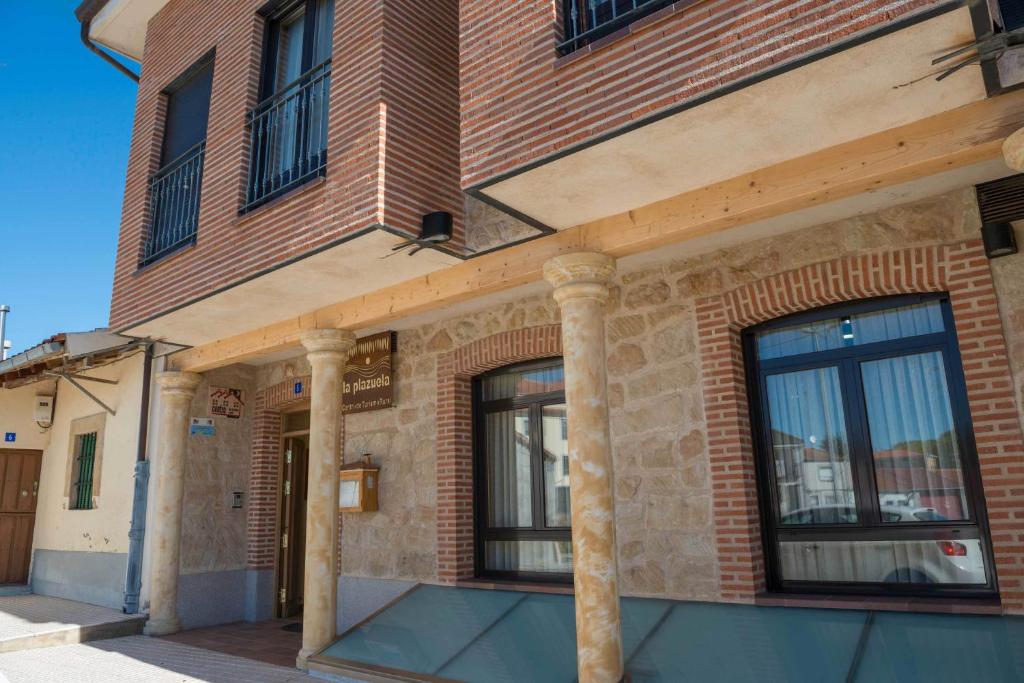 a brick building with windows on a street at Hotel Rural La Plazuela in Aldealengua