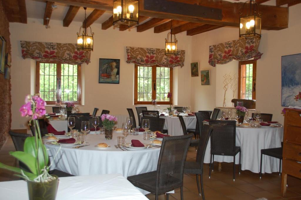 un comedor con mesas y sillas blancas y ventanas en Molino De La Ferrería, en Villacorta