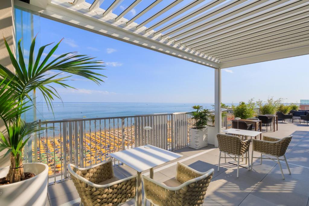 eine Terrasse mit einem Tisch und Stühlen auf dem Balkon in der Unterkunft DIVA HOTEL LIGNANO - Adults Only in Lignano Sabbiadoro