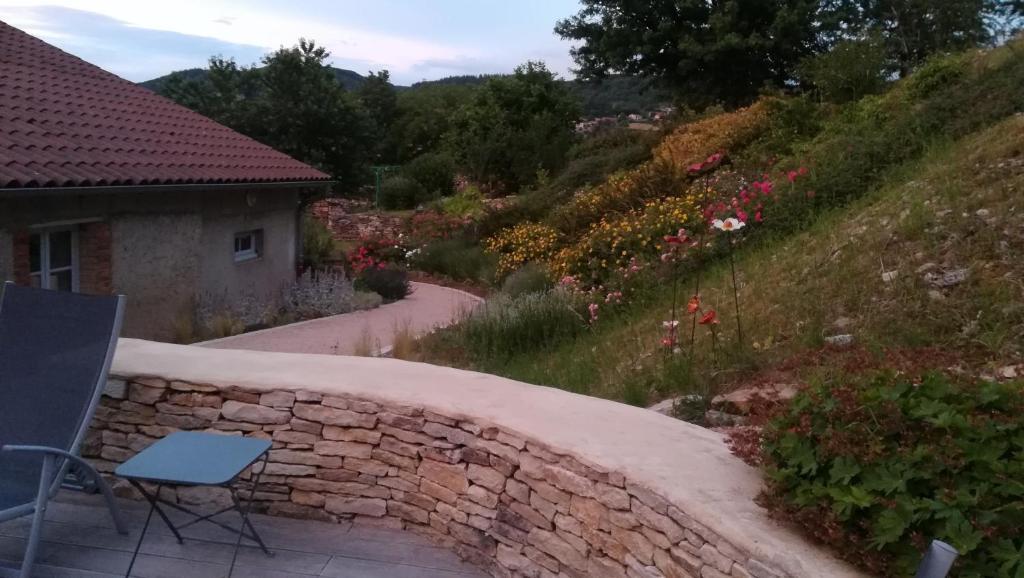 a stone wall with a table and a chair on a patio at Les chambres de Blanot in Blanot