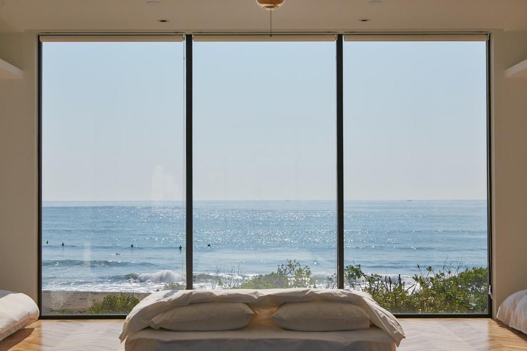 a bedroom with a large window overlooking the ocean at THE CHIKURA UMI BASECAMP in Awa