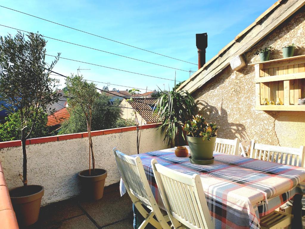 einen Tisch und Stühle auf einem Balkon mit Pflanzen in der Unterkunft Le Grenier, Climatisation Terrasse Wi-Fi Netflix 15 mn coeur de ville in Béziers
