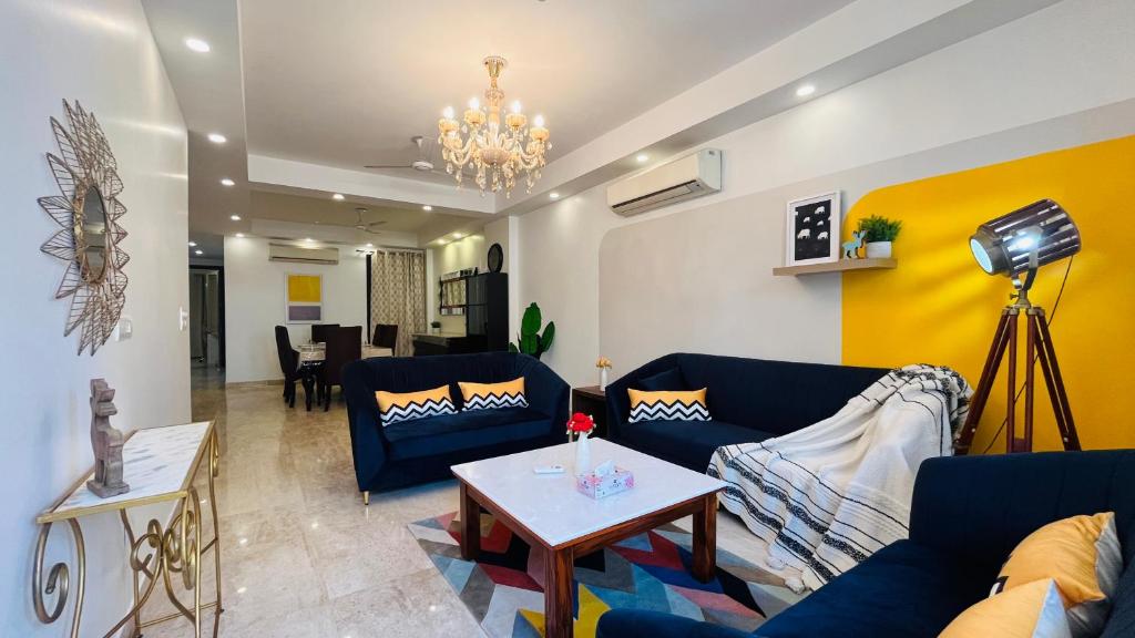 a living room with blue couches and a table at Olive Service Apartments - Greater Kailash in New Delhi