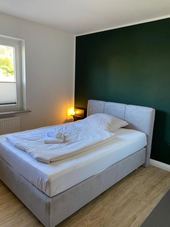 een wit bed in een slaapkamer met een groene muur bij S17 ferienappartments in Flensburg