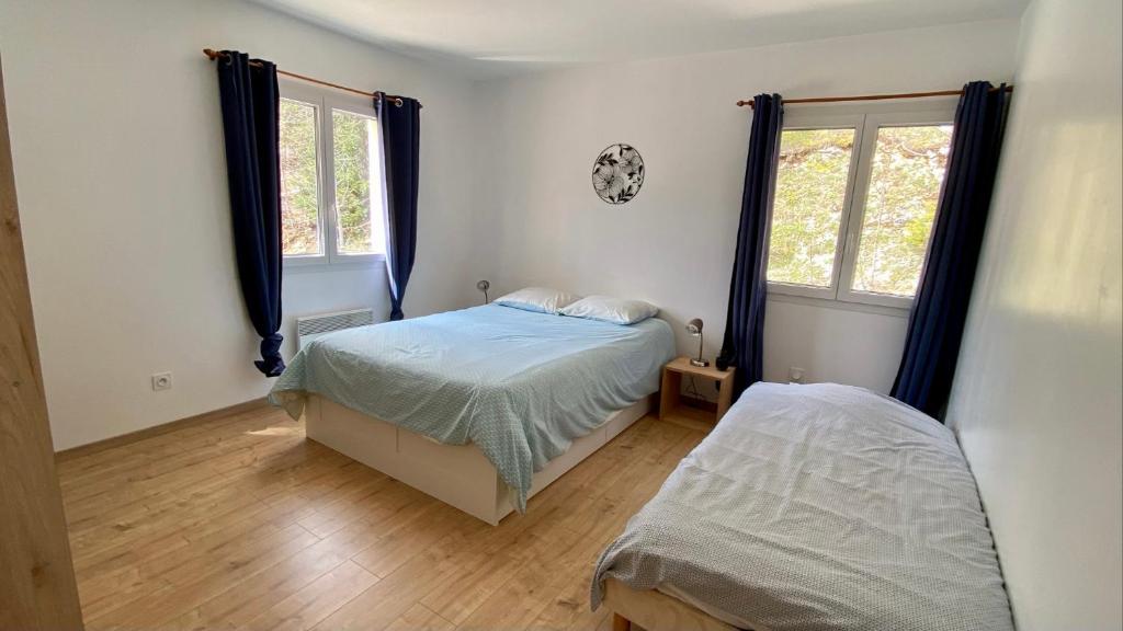 a bedroom with two beds and two windows at Appartement idéal pour été et hiver, situé au pied des pistes de ski et des sentiers de randonnée in Prémanon