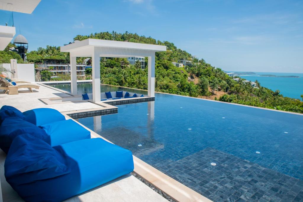 una piscina con sillas azules y el océano en el fondo en BLUE ELEPHANT Luxury Pool Villa Koh Samui by Blue Mountain Villas en Koh Samui