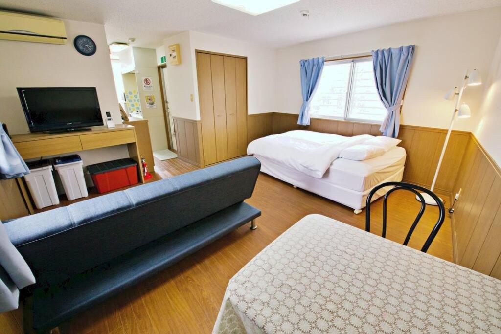 1 dormitorio con sofá, cama y TV en ピースリー安里301, en Tomari