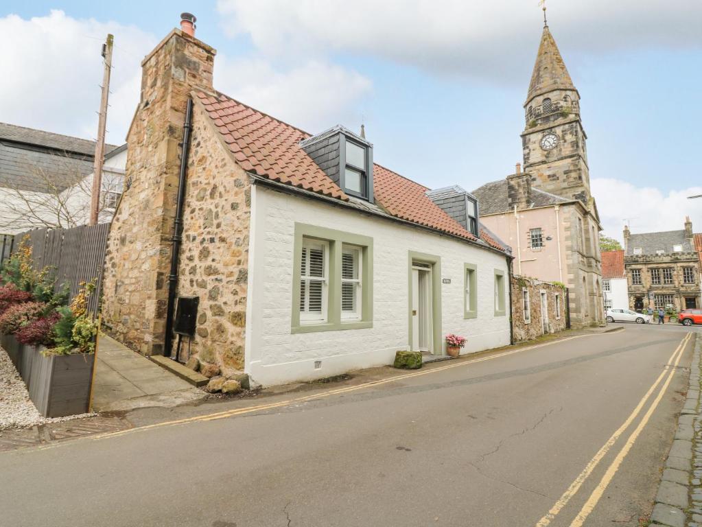 a small white building on a street with a clock tower at Dunira in Cupar