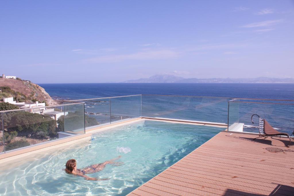 a woman in a swimming pool with a view of the ocean at La Residencia Tarifa in Tarifa