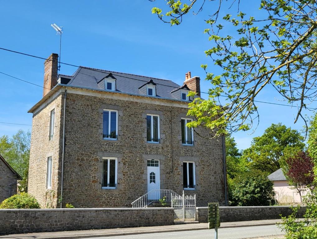 an old brick house on the side of a street at Gite de la Fontaine in La Bazouge-des-Alleux
