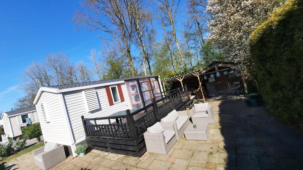 een wit tiny house met een veranda en een trap bij Kajuit423 6pers 5sterren vakantiepark Bergumermeer aan het water in Friesland met zwembad in Suameer
