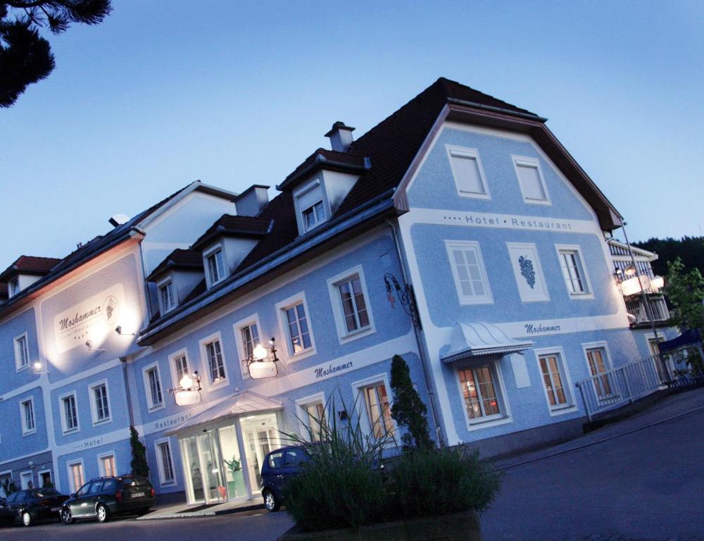 un grand bâtiment blanc avec des voitures garées devant lui dans l'établissement Landhotel Moshammer, à Waidhofen an der Ybbs