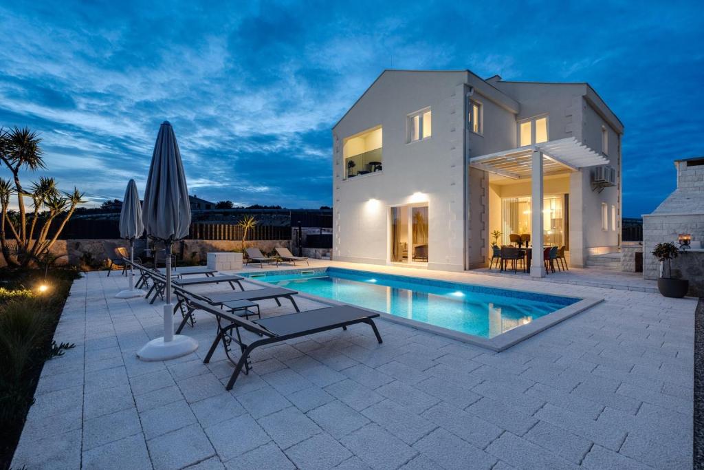 Grohote的住宿－Villa Ora with Heated pool, Whirlpool, 4 bedrooms，夜间带游泳池的别墅