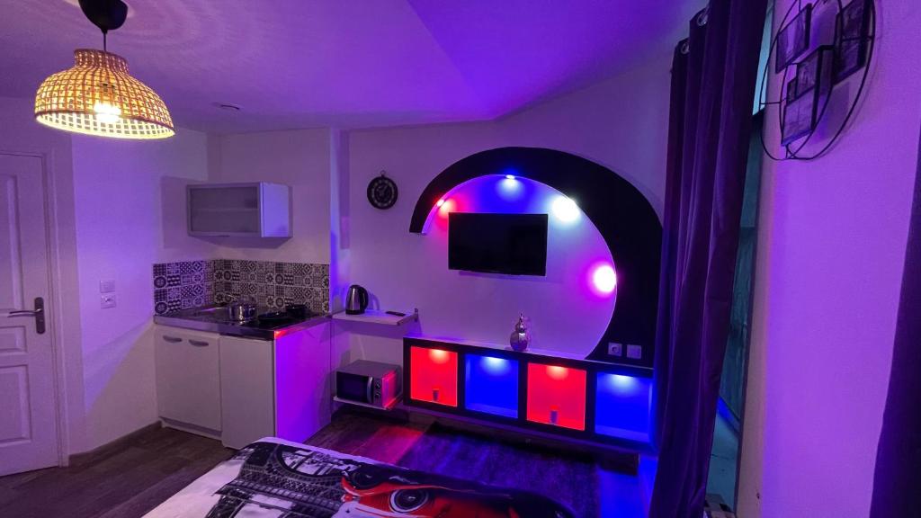 a kitchen with purple and blue lights in a room at Le cocon du Nil jolie studio in Douai