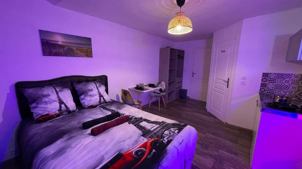 a purple bedroom with a bed in a room with a table at Le cocon du Nil jolie studio in Douai