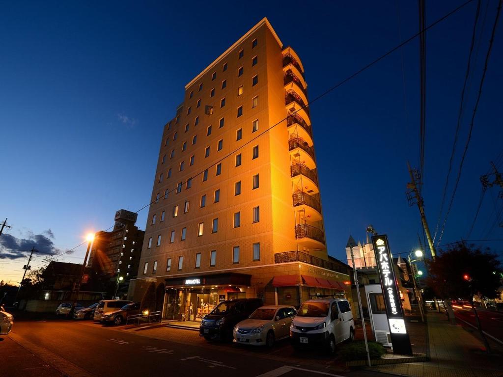 a tall building with cars parked in front of it at APA Hotel Isesaki-Eki Minami in Isesaki
