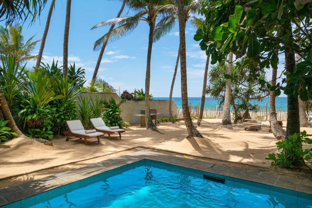 una piscina frente a una playa con palmeras en Taru Villas 906 - Hikkaduwa en Hikkaduwa
