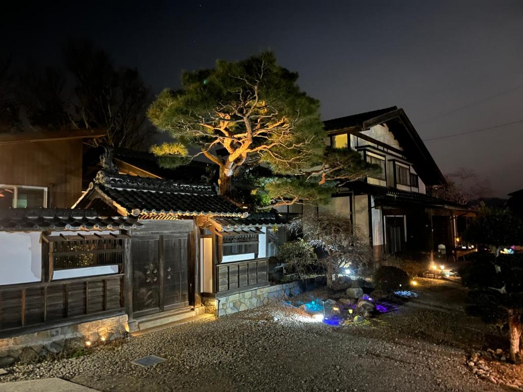 a house with a tree in front of it at night at 離れの宿　かぶろの庭 in Matsukawa