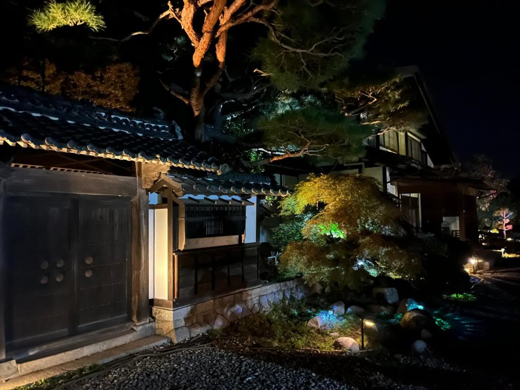 a house at night with a tree in front of it at 離れの宿 かぶろの庭 in Matsukawa