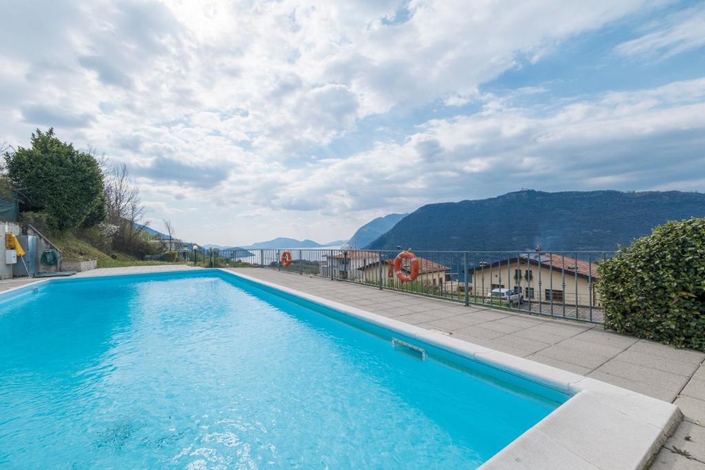 a blue swimming pool with mountains in the background at De Gasperi 14 in Sale Marasino