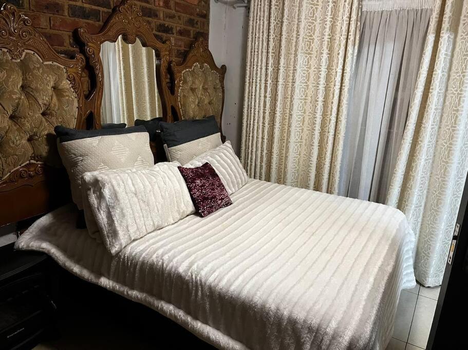 a bed with white sheets and pillows in a bedroom at Berry’s cosy cottage in Pretoria