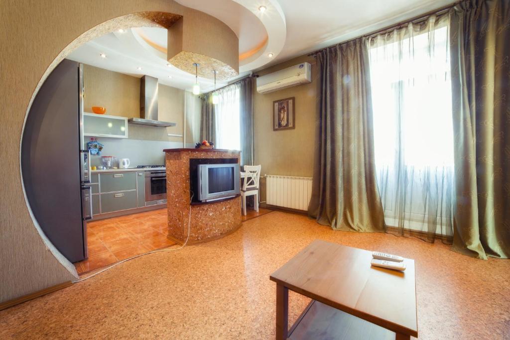 a living room with a table and a tv and a kitchen at Five Stars Comfortable Kvartira in Chelyabinsk