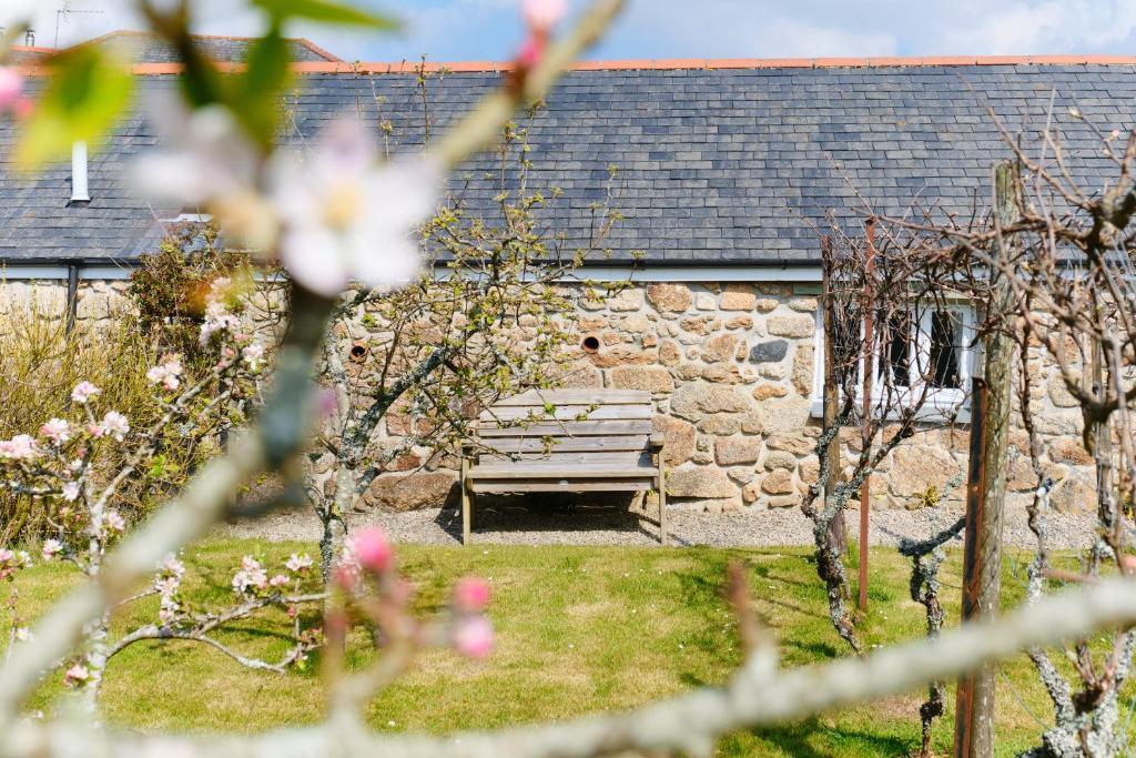 a park bench in front of a stone building at Cobblestone Cottage in Penzance