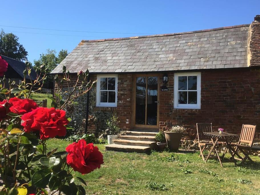 a brick house with red roses in front of it at The Calf Shed at Broxhall Farm in Canterbury
