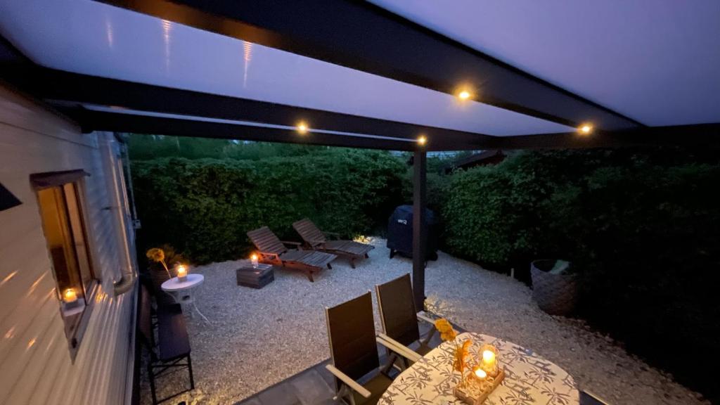 eine Terrasse mit einem Tisch, Stühlen und Lampen in der Unterkunft PURE - Chalet Zeeland - garden out of sight in Hoek