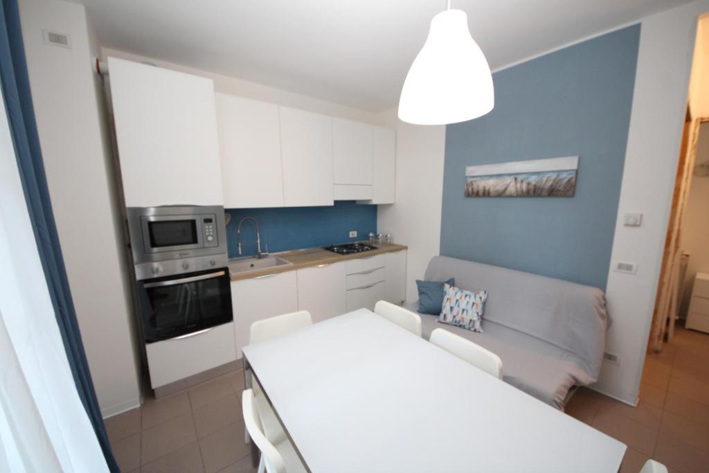 una pequeña cocina con una mesa blanca y un sofá en Residence Verdena appartamento 02 en Rosolina Mare